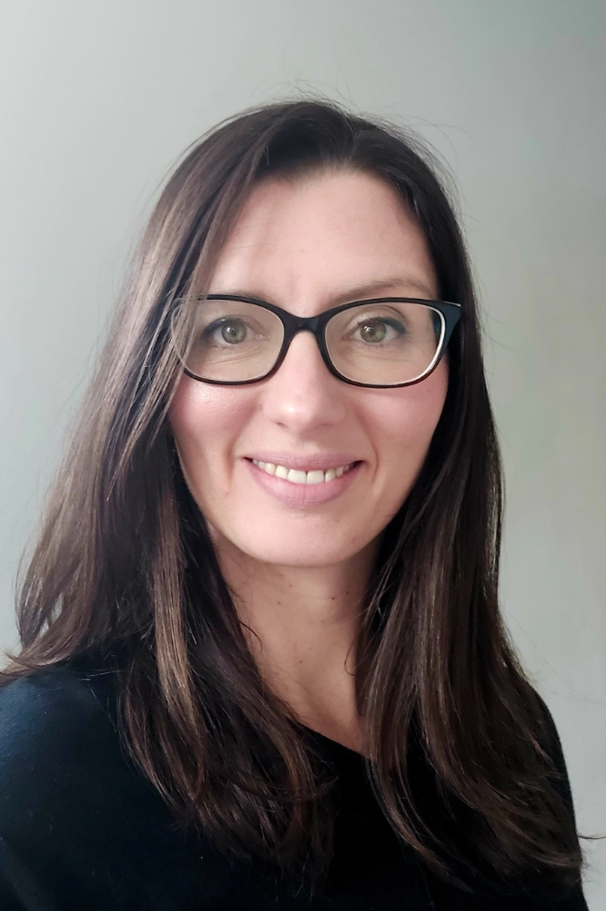 A woman with glasses and a black shirt.